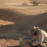 Geologe untersucht Gesteinsproben an einem Lithium-Explorationsstandort in trockener Landschaft