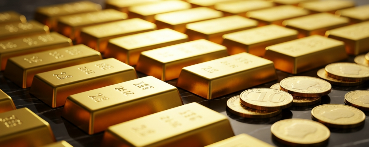 Goldbarren und Anlagemünzen auf dunklem Untergrund in warmem Licht
