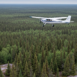 Kleines Vermessungsflugzeug über borealer Landschaft in Ontario für einen geophysikalischen Airborne-Survey