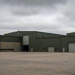 Industrieanlage zur Rüstungsproduktion unter bewölktem Himmel in militärischen Grau- und Grüntönen