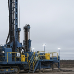 Bohranlage im Athabasca-Becken unter bedecktem Himmel in Stahl-Blau und Betongrau