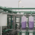 ISR-Verarbeitungsanlage für Seltene Erden mit grünen Rohren und lilafarbenen Oxidrückständen in Sammelbehältern