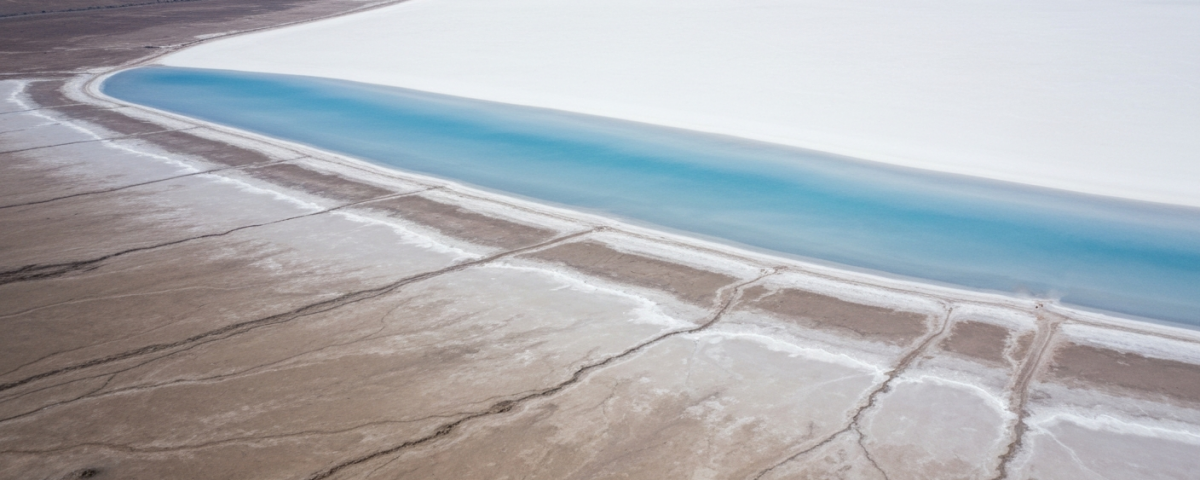 Luftaufnahme eines Salars mit weißer Salzkruste und himmelblauen Verdunstungsbecken bei Mittagslicht