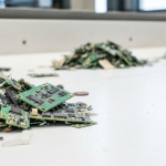 Zerkleinerter Elektronikschrott mit Magnetfragmenten auf weißer Sortierfläche in einer Recyclinganlage