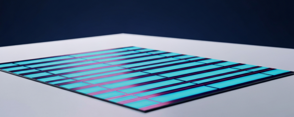 Siliziumwafer mit schillernden Cyan-Magenta-Interferenzmustern auf weißem Untergrund