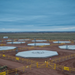 Luftaufnahme einer ISR-Urananlage in Wyoming mit Bohrkopf-Reihen und Sicherheitszäunen unter stahlblauem Himmel