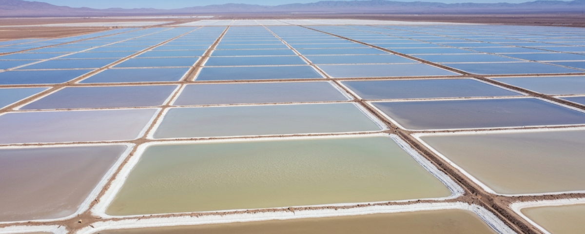 Luftaufnahme von Lithium-Eindampfungsbecken in einem Salar mit weißer Salzkruste und himmelblauen Becken