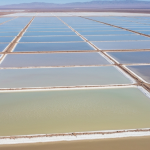 Luftaufnahme von Lithium-Eindampfungsbecken in einem Salar mit weißer Salzkruste und himmelblauen Becken