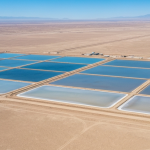 Luftaufnahme eines Lithium-Verdunstungsteich-Komplexes in einer Wüstenregion mit salzweißem Boden und hellblauen Becken
