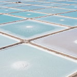 Luftaufnahme eines Lithium-Sole-Verdunstungsteich-Rasters in einem Salar mit weißer Salzkruste und himmelblauen Teichen