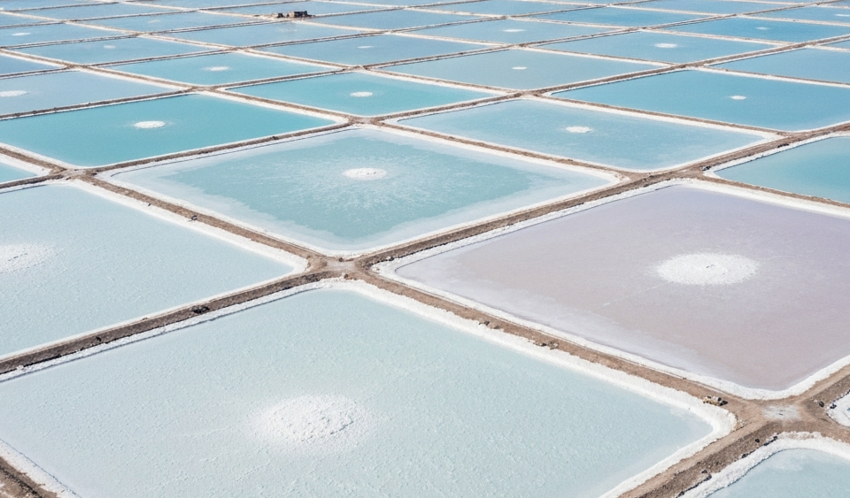 Luftaufnahme eines Lithium-Sole-Verdunstungsteich-Rasters in einem Salar mit weißer Salzkruste und himmelblauen Teichen
