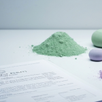 Explorationslizenz-Dokument neben Seltene-Erden-Oxidproben in gedämpften Farben auf weißer Unterlage