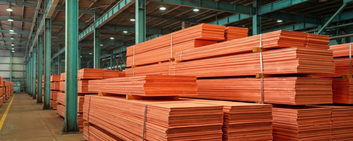 Kupferkathoden-Stapel in einer Verarbeitungsanlage mit rötlich-orangefarbener Metalloberfläche und grüner Patina