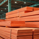 Kupferkathoden-Stapel in einer Verarbeitungsanlage mit rötlich-orangefarbener Metalloberfläche und grüner Patina