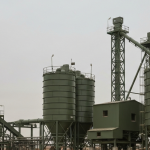 Industrielle Aufbereitungsanlage für Seltenerdmineralien unter bedecktem Himmel in gedämpften Grau- und Grüntönen