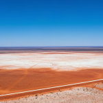 Luftaufnahme eines Explorationsgebiets im australischen Outback mit weitläufiger Landschaft und blauem Himmel