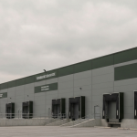 Industrielle Logistikanlage unter bedecktem Himmel, militärgrüne Fassade