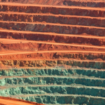 Luftaufnahme eines Kupfer-Tagebaus mit rotorangen Terrassen und türkisfarbener Oxidationszone