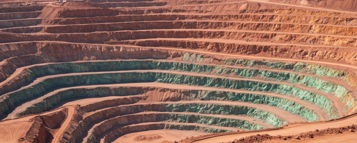 Luftaufnahme eines Kupfer-Tagebaus in der chilenischen Atacama mit terrassenförmigen Gesteinsschichten in Rot- und Ocker