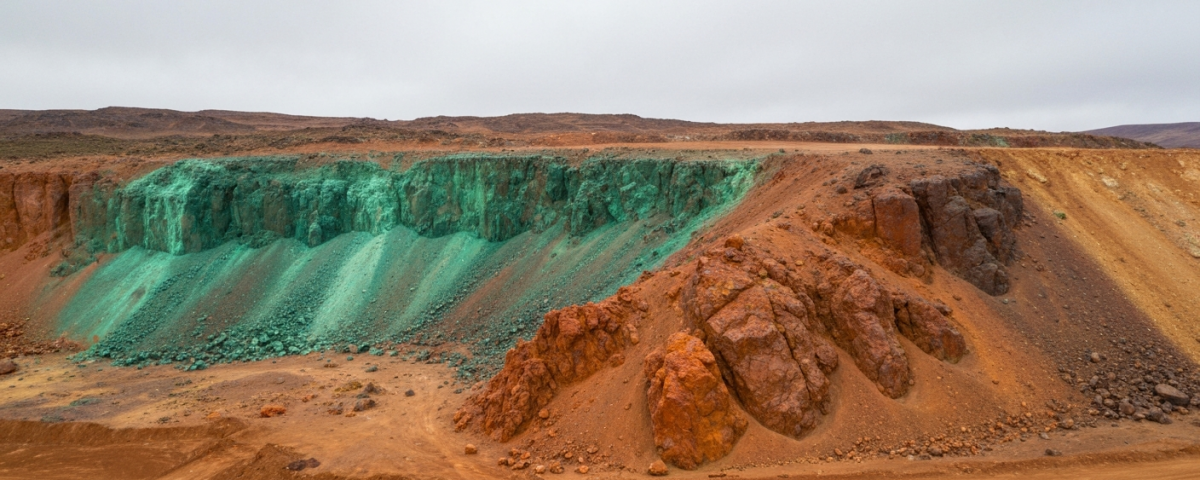 Luftaufnahme eines Explorationsgeländes in den Anden mit rötlich-orangefarbenem Gestein und grünen Malachitspuren