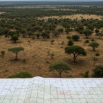 Luftaufnahme einer westafrikanischen Explorationslandschaft mit geologischem Kartenraster im Vordergrund