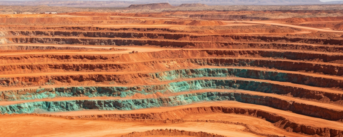 Luftaufnahme eines Kupfer-Tagebaus in Arizona mit rotbraunen Gesteinsschichten und grüner Malachit-Verwitterung