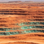 Luftaufnahme eines Kupfer-Tagebaus in Arizona mit rotbraunen Gesteinsschichten und grüner Malachit-Verwitterung