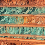 Kupfer-Tagebau mit rötlichen Gesteinsformationen und grüner Oxidation an den Terrassen
