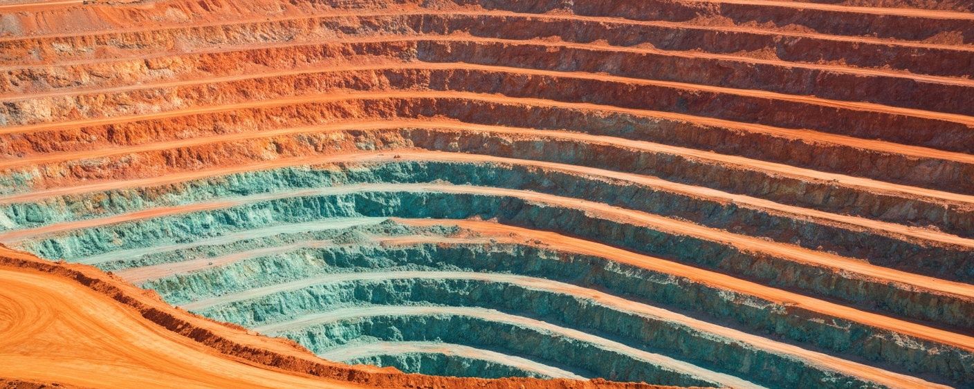 Luftaufnahme eines Kupfer-Tagebaus mit rotorangen Erzbänken und blaugrünen Oxidationszonen