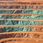 Luftaufnahme eines Kupfer-Nickel-Tagebaus mit terrassierten Felswänden und grün-türkiser Malachit-Oxidation