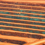 Luftaufnahme eines Kupfertagebaus mit rötlich-orangen Gesteinsformationen und blaugrünen Oxidationsspuren