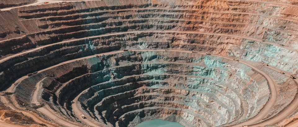 Luftaufnahme eines terrassierten Kupfertagebaus in den Anden mit rötlich-orangen Gesteinsschichten